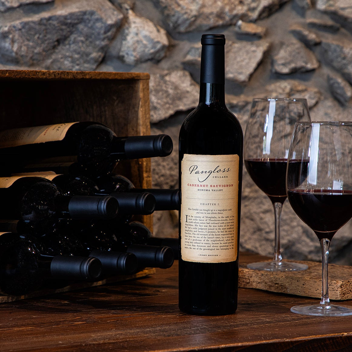 Wine bottle with a wooden crate and glasses on a stone background