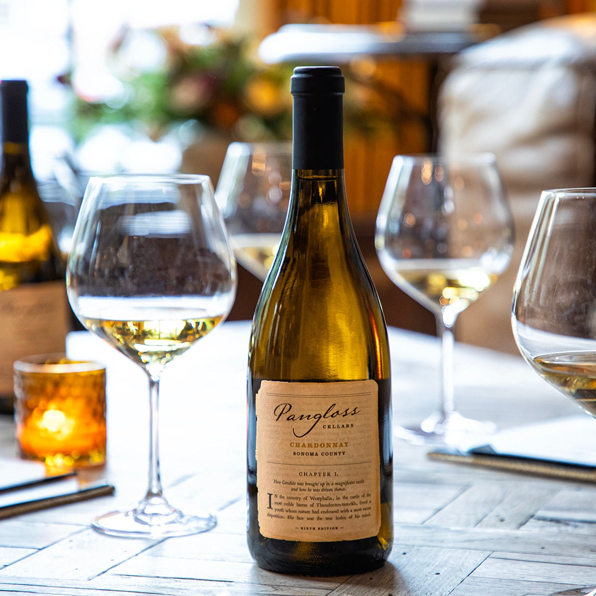 Wine bottle with a label on a table with wine glasses filled with white wine.