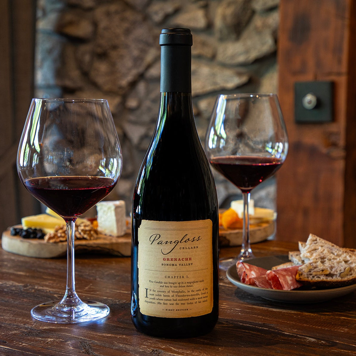 Wine bottle with two glasses of red wine on a wooden table with snacks.
