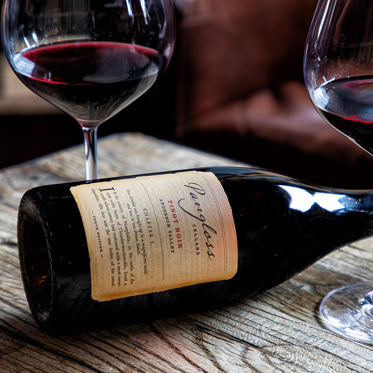 Wine bottle and two glasses of red wine on a wooden surface