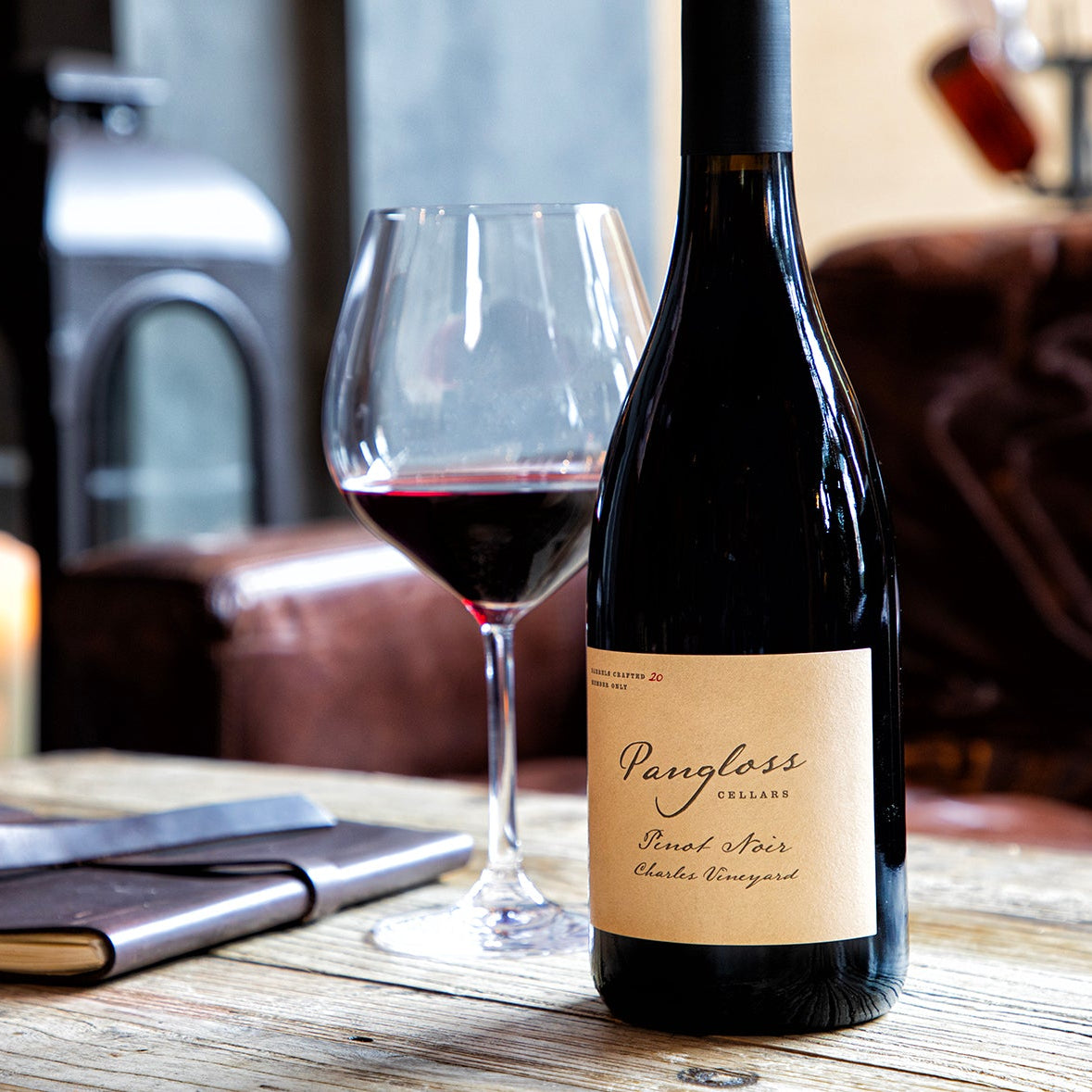 Bottle of wine and glass on a table with a cozy background