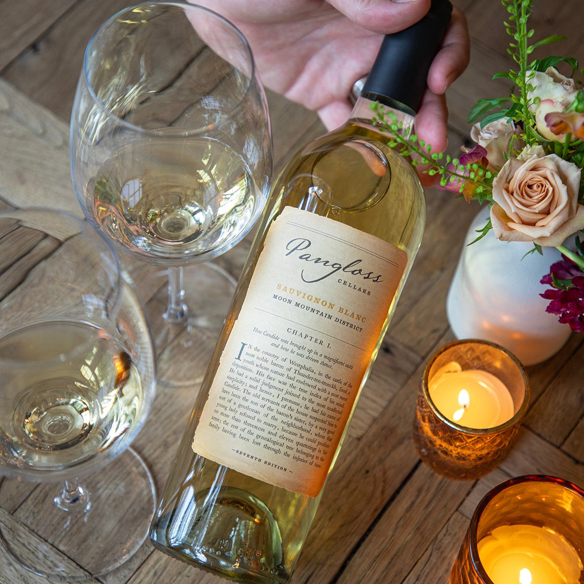 Bottle of wine with two glasses and a candle on a wooden surface