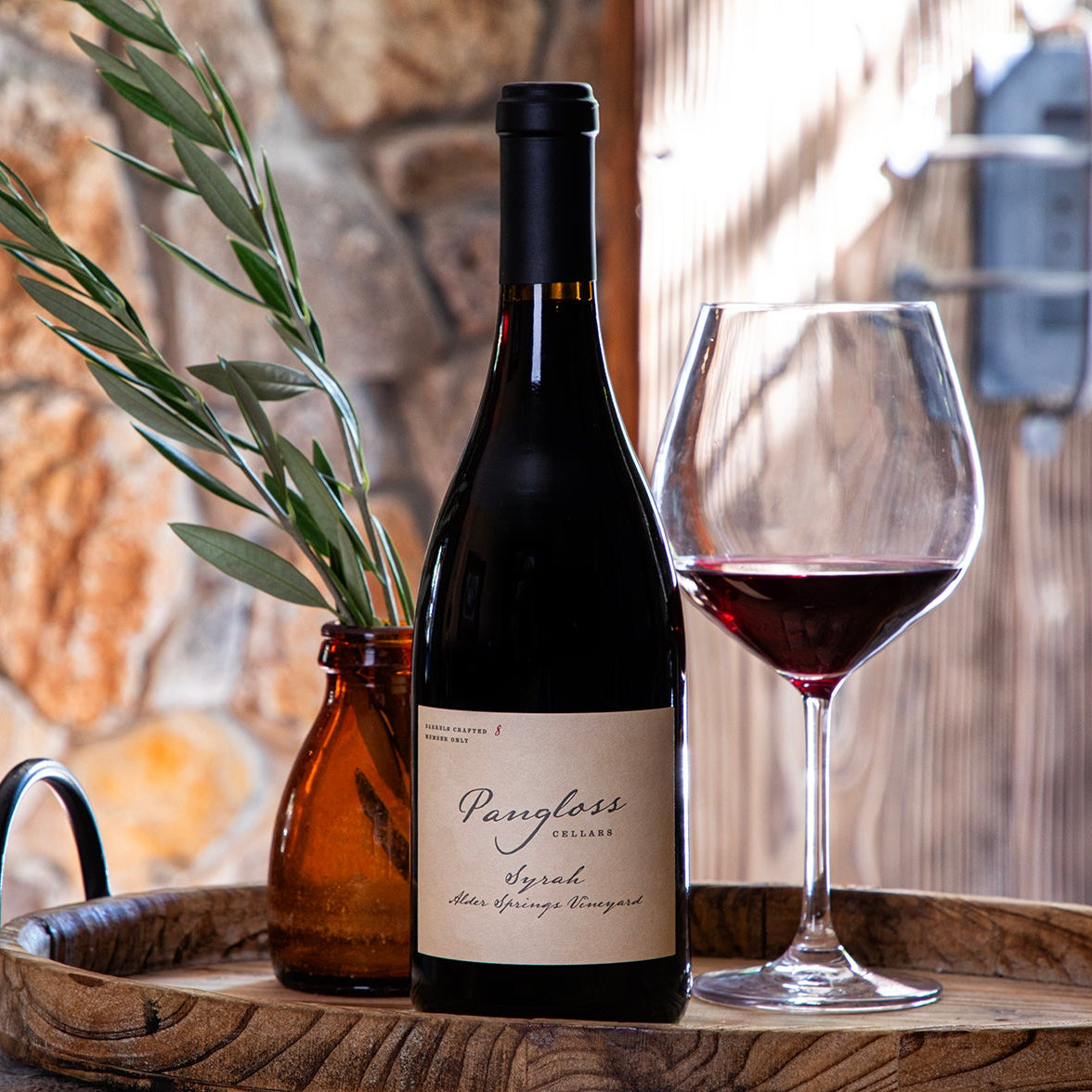 Wine bottle and glass on a wooden tray with stone wall background