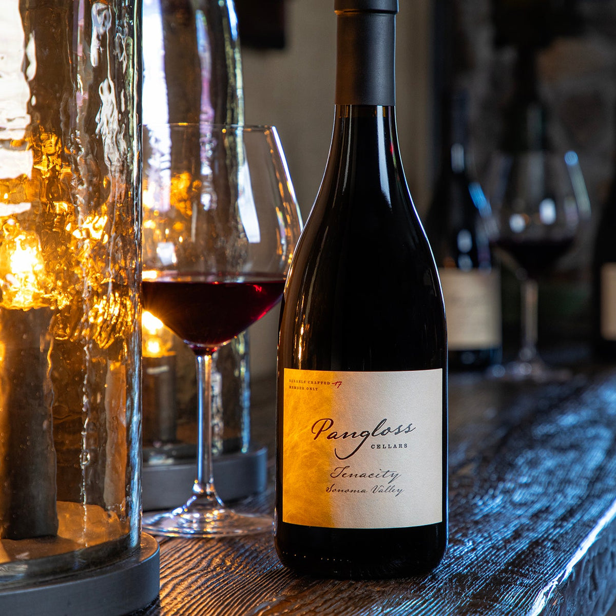 Wine bottle with a label on a bar counter with glasses and lights in the background