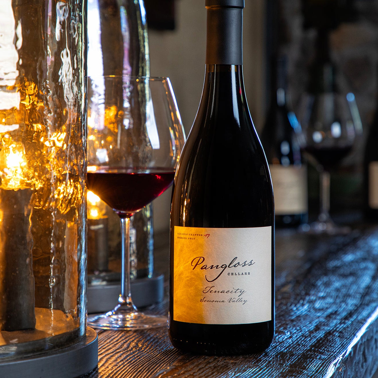 Wine bottle with a label on a bar counter with glasses and lights in the background